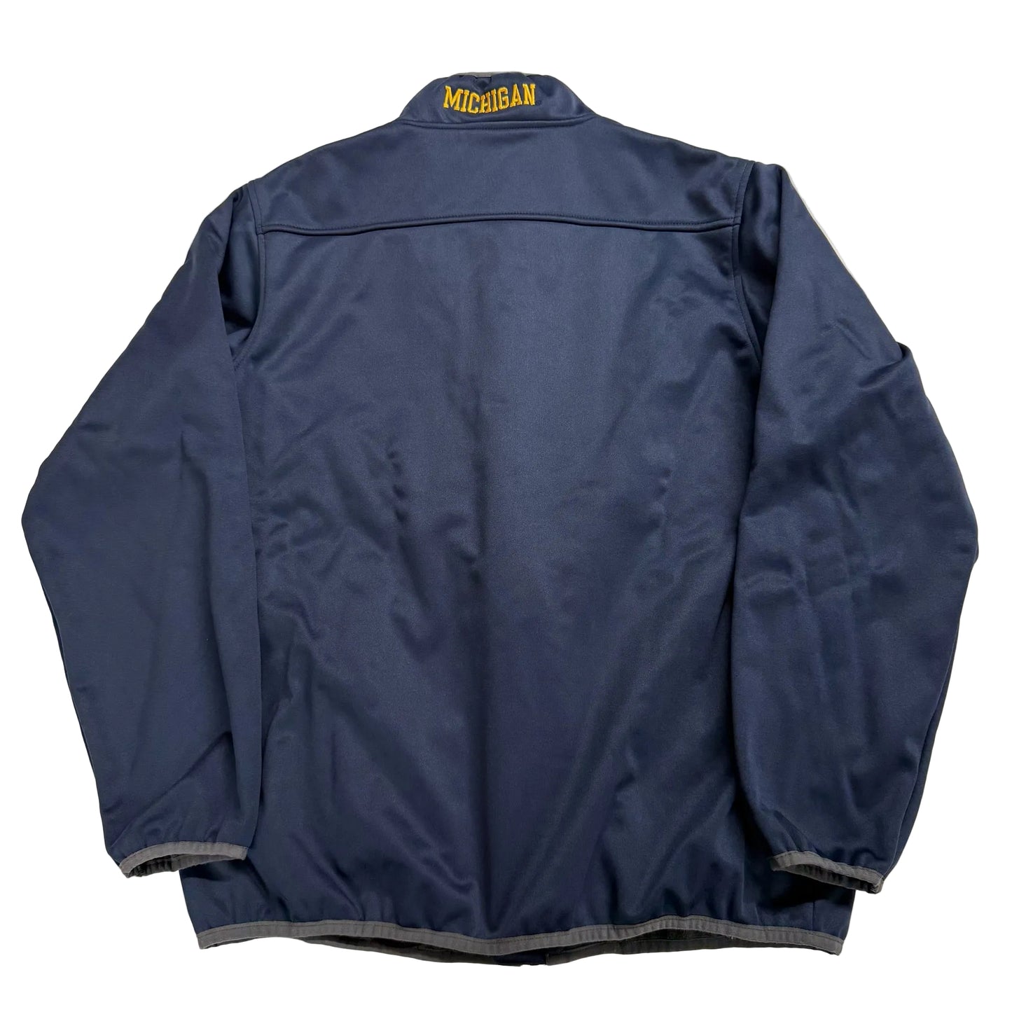 Blue jacket with 'Michigan' text on the back, laid flat on a light-colored surface.