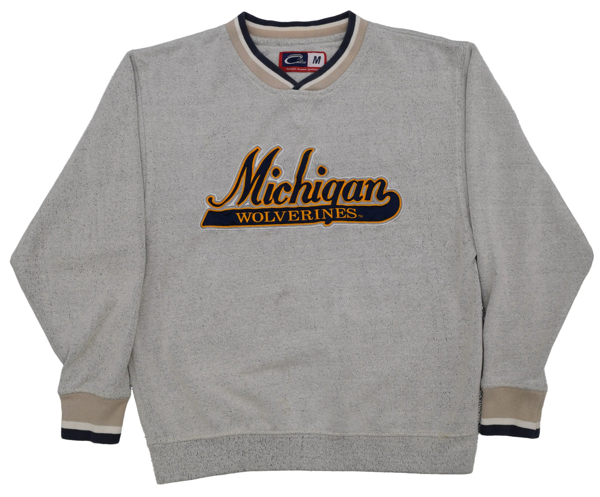 University of Michigan gray crewneck sweatshirt featuring 'Michigan Wolverines' embroidered on the chest in black and gold, with beige and navy ribbed trim on the collar, cuffs, and hem.