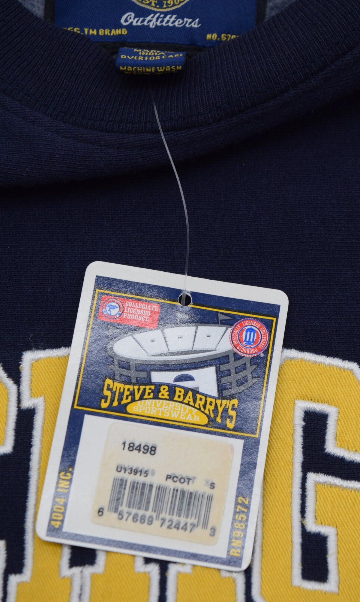 Close-up of a University of Michigan navy blue sweatshirt with yellow and white lettering, featuring a hanging tag for Steve & Barry's.