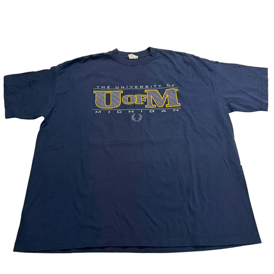Navy blue t-shirt with 'The University of UofM Michigan' printed on it, laid flat on a white surface.