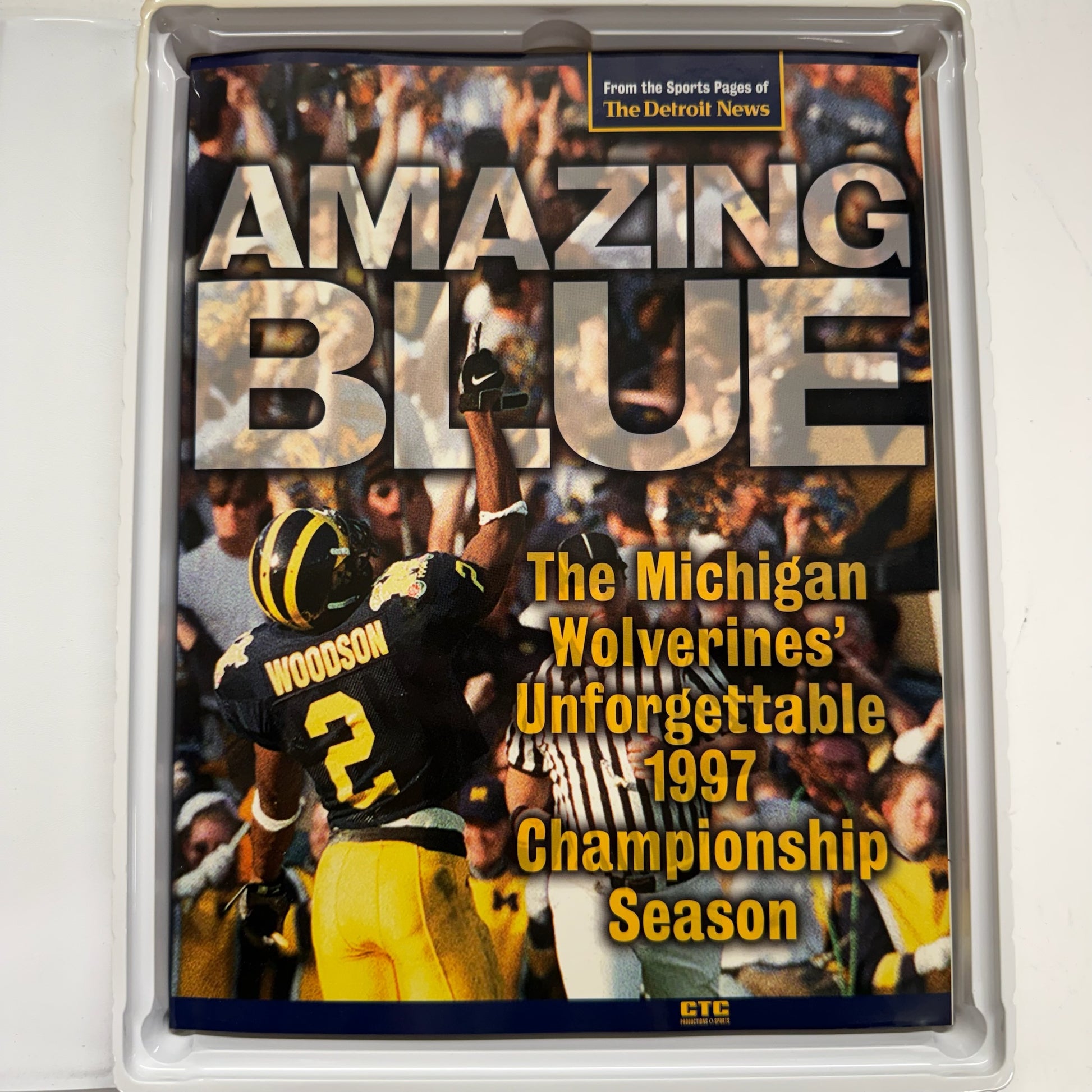 Book cover titled 'Amazing Blue' featuring a football player and text about the Michigan Wolverines' 1997 championship season.