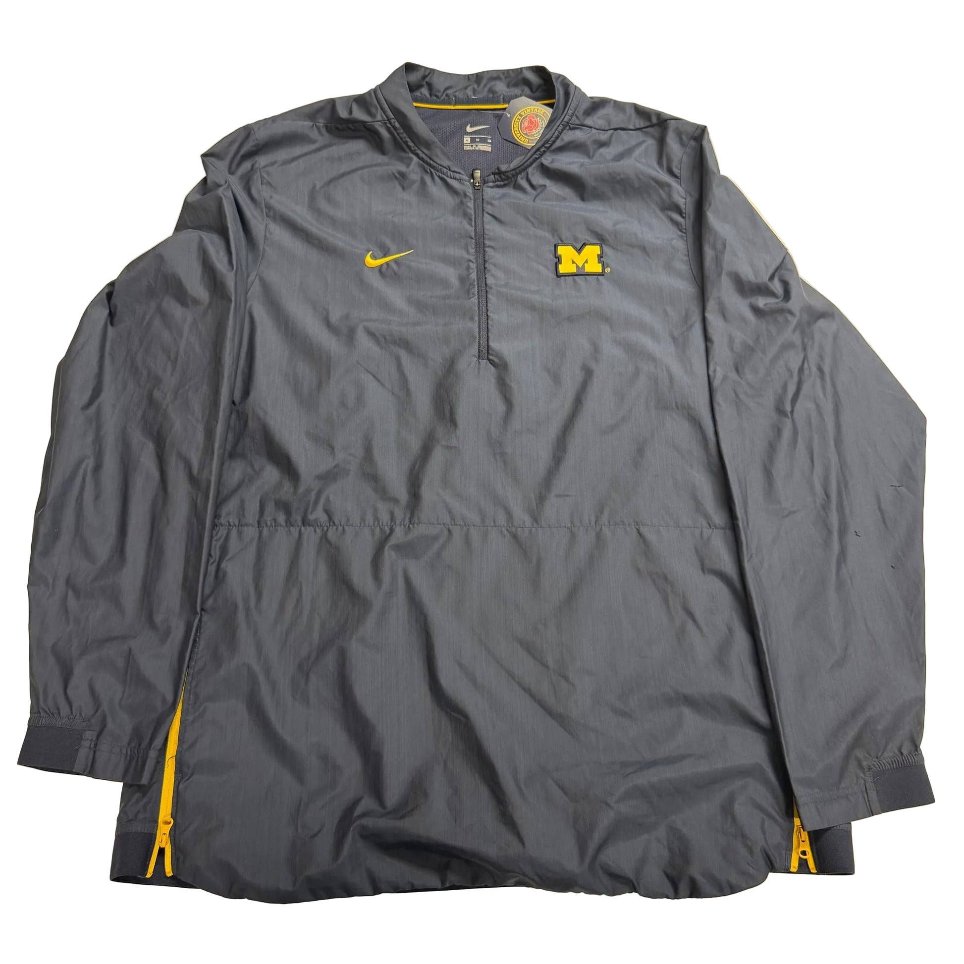 Gray jacket with Nike logo and Michigan Wolverines emblem on a beige background